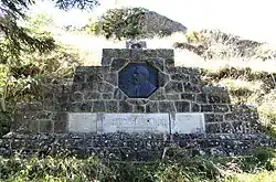 Photographie d'un monument funéraire en pierre avec une plaque en bronze.