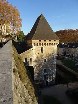 Photographie en couleurs d'une tour carrée portant des mâchicoulis et une toiture pyramidale.