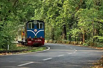 Un train tiré par une locomotive diesel sur les bords d'une route.