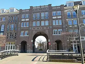 Photographie d'un immeuble moderne de brique imitant la forme d'une poterne.