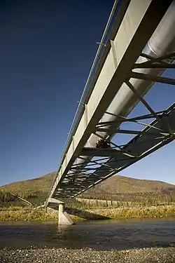 Photo d'un pont traversant un cours d'eau, sur lequel est installé l'oléoduc.