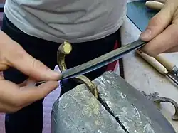 Polissage d'une pièce de bronze à l'aide d'un papier émeri abrasif pour rendre la surface plus brillante