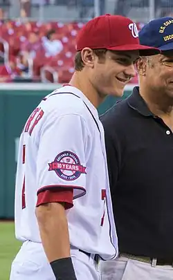 Un jeune joueur de baseball en tenue blanche portant une casquette rouge.