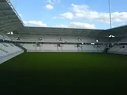 Vue intérieure d'un stade de football avec un terrain et de tribunes vides.