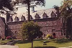 Façade d'un bâtiment en pierres, avec un arbre au premier plan.