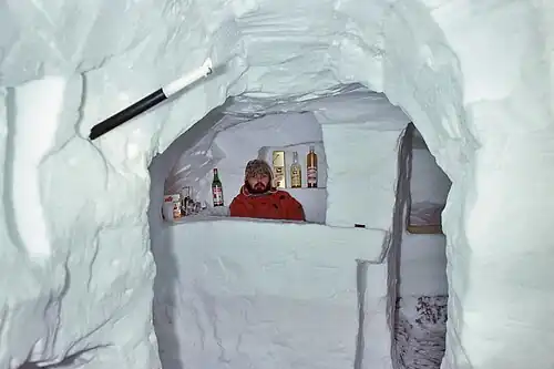 Trou à neige de grande dimension aménagé en bar dans une congère.