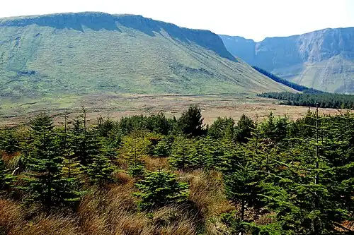 Photographie de falaises dominant un paysage de landes.