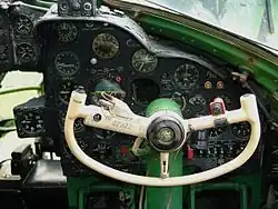 photographie en couleur montrant le manche en forme de demi-volant du copilote, avec les cadrans des instruments de la planche de bord en arrière-plan