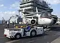 Tracteur de pont d'envol de l'US Navy en action avec un Lockheed S-3 Viking.