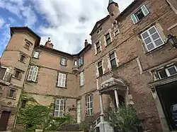 Photographie en contre-plongée d'un bâtiment à deux corps perpendiculaires, en briques rouges et aux fenêtres blanches.