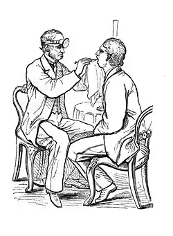 gravure ancienne montrant un médecin assis, ayant fixé son miroir lumineux sur son front et examinant la bouche d'un patient assis en face d elui à l'aide d'un miroir laryngé