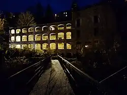 Photographie de l'ancienne usine du Faux-Martel éclairée de nuit en jaune.