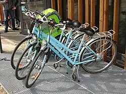 Plusieurs vélos bleus devant la Vélostation.