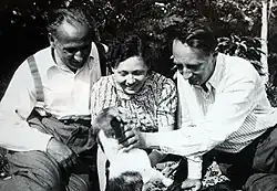 Trois personnes sont assis face à un animal, l'homme à gauche est Vítězslav Kaprál, la femme au centre est la compositrice Vítězslava Kaprálová et l'homme à droite, qui caresse l'animal, est Bohuslav Martinů. La photo est en noir et blanc.