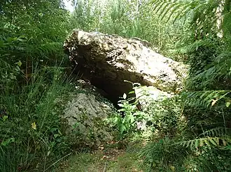 Un bloc de pierre brute posé hoizontalement sur trois autres blocs de pierre brute verticaux.