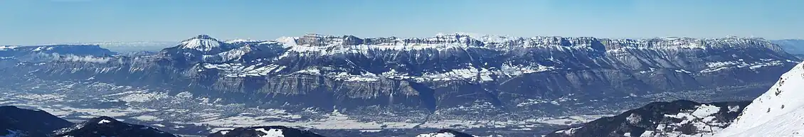 Vue panoramique sur de longues parois rocheuses quasiment ininterrompues par-delà une vaste vallée.