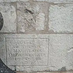 photo d'épitaphe sous un crâne encastré dans le mur Est de l'église
