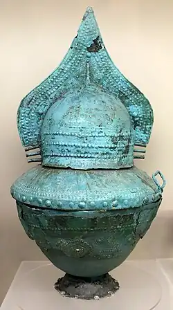 Vase cinéraire à couvercle en forme de casque à crête haute, bronze, nécropole des quatre fontaines, tombe à puits AA1, 750 av. J.-C.