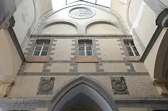 Photo couleur montrant le détail de l'extrémité est du cloitre nord, avec, de gauche à droite, les blasons de l'abbé Jean Patoul et celui de Bonne-Espérance.