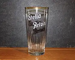 Vieux verre à bière Stella Artois avec écriture émaillée.