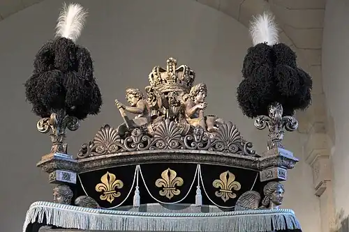 Palmettes et fleurs de lys sculptées, surmontées de plumes.