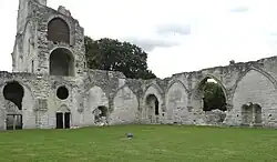 Deux pans de murs portant des arcs formerets au centre d'une pelouse et surmontés de l'abbatiale