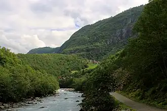 Bâtiments de ferme rouges près d'un petit pré dans une vallée boisée.