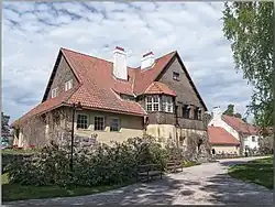 Maison vue de trois-quart, façade jaune pâle, tuiles rouges.