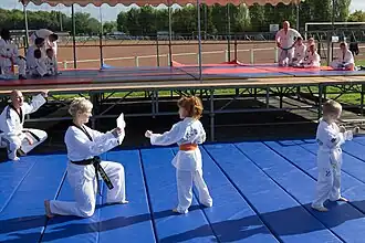 Des enfants et des adultes faisant une démonstration de sport de combat.