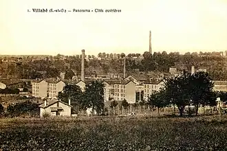 Vue d'une cité ouvrière sur une carte postale ancienne : petits immeubles collectifs et cheminées d'usines.