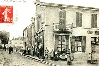 Vue de bâtiments du début du XXe&nbsp;siècle en bord de rue sur une carte postale ancienne.