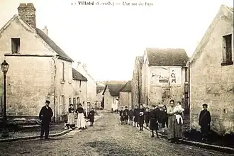 Vue d'une rue au début du XXe&nbsp;siècle ; mairie à gauche et école à droite