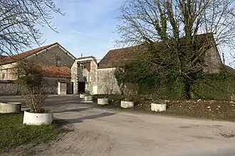 Vue de l'extérieur d'une ferme entourée de haut murs de pierre