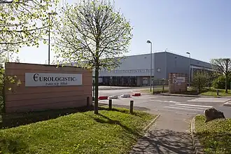 vue d'un bâtiment industriel de couleur grise et d'un portail d'entrée en brique