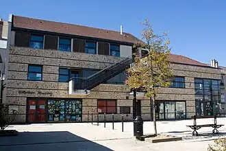 Vue d'un bâtiment récent à étages, en meulière et verre ; escalier extérieur.