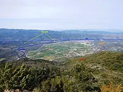 La bajada de Vinça - son étendue approximative est indiquée par la ligne blanche hachurée. La ligne bleue représente le cours actuel de la rivière Llentillà.