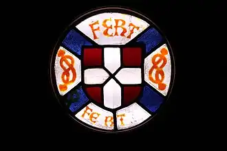 Vitrail aux armes d’Amédée VIII, réalisé par le verrier suisse Janin Loysel (verre et plomb, collection privée, déposée à la Fondation du château de Ripaille). Au centre, les armes de la maison de Savoie — de gueule à la croix d’argent, entourées de deux nœuds ou lacs d’amour et de la devise FERT de la famille.