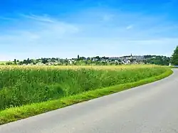 Vue générale du bourg côté sud depuis la nationale  avant le lieu-dit de la Croix de l'Abbaye. Le centre du village est au sommet de la colline à 85 mètres d'altitude.