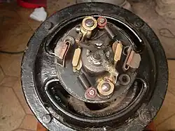 Vue de l'intérieur du coupleur centrifuge. À remarquer les deux masselottes en bronze maintenues chacune par un ressort de force différente afin que les contacts se fassent en deux temps lors de l’accélération du moteur