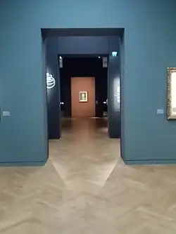 Autoportrait aux lunettes dans l'axe des galeries du nouveau Salon Goya depuis 2023.