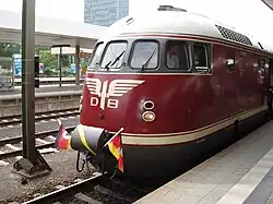 Un train rouge et or orné d'un pavillon allemand en quai.