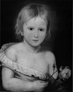 Portrait en noir et blanc, montrant en buste un tout jeune enfant, portant une petite chemise qui tombe de son corps, révélant la moitié de sa poitrine. Il a une courte cheveleure blonde et tient une rose.