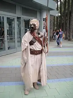 Homme costumée avec un masque et un fusil.