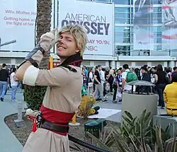 Personne déguisée portant une perruque blonde et agissant de manière théâtrale.