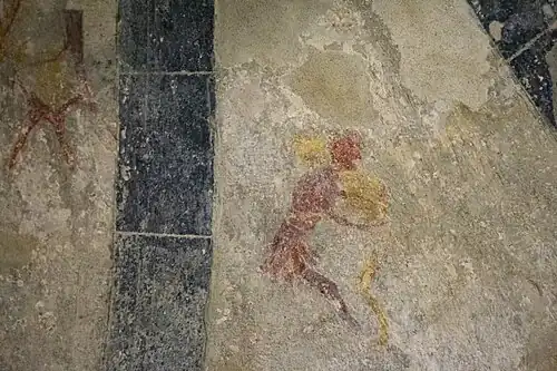 Fresque médiévale très abîmée montrant deux hommes en train de lutter.