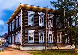 Photographie d'un bâtiment en bois marron avec les cadres des fenêtres bleues possédant deux étages.