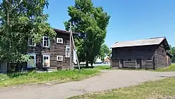 Photographie de deux bâtiments en bois marrons ayant un étage en plus du rez-de-chaussée.