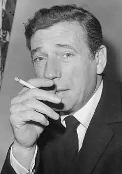 Portrait de trois-quarts en noir et blanc d'Yves Montand fumant une cigarette lors d'une représentation à La Haye