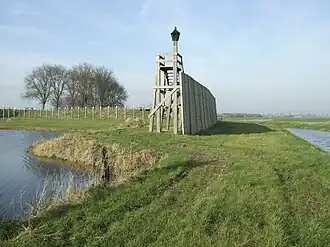 Photographie en couleurs d'une ancienne digue et d'un terrain entourés par les eaux