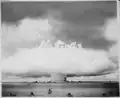 Vue aérienne du test Baker lors de l'opération Crossroads sur l'atoll de Bikini en 1946 quelques secondes après la photo précédente : le nuage de condensation a pris la forme d'un anneau, laissant apparaitre la base de la colonne d'eau expulsée du lagon.